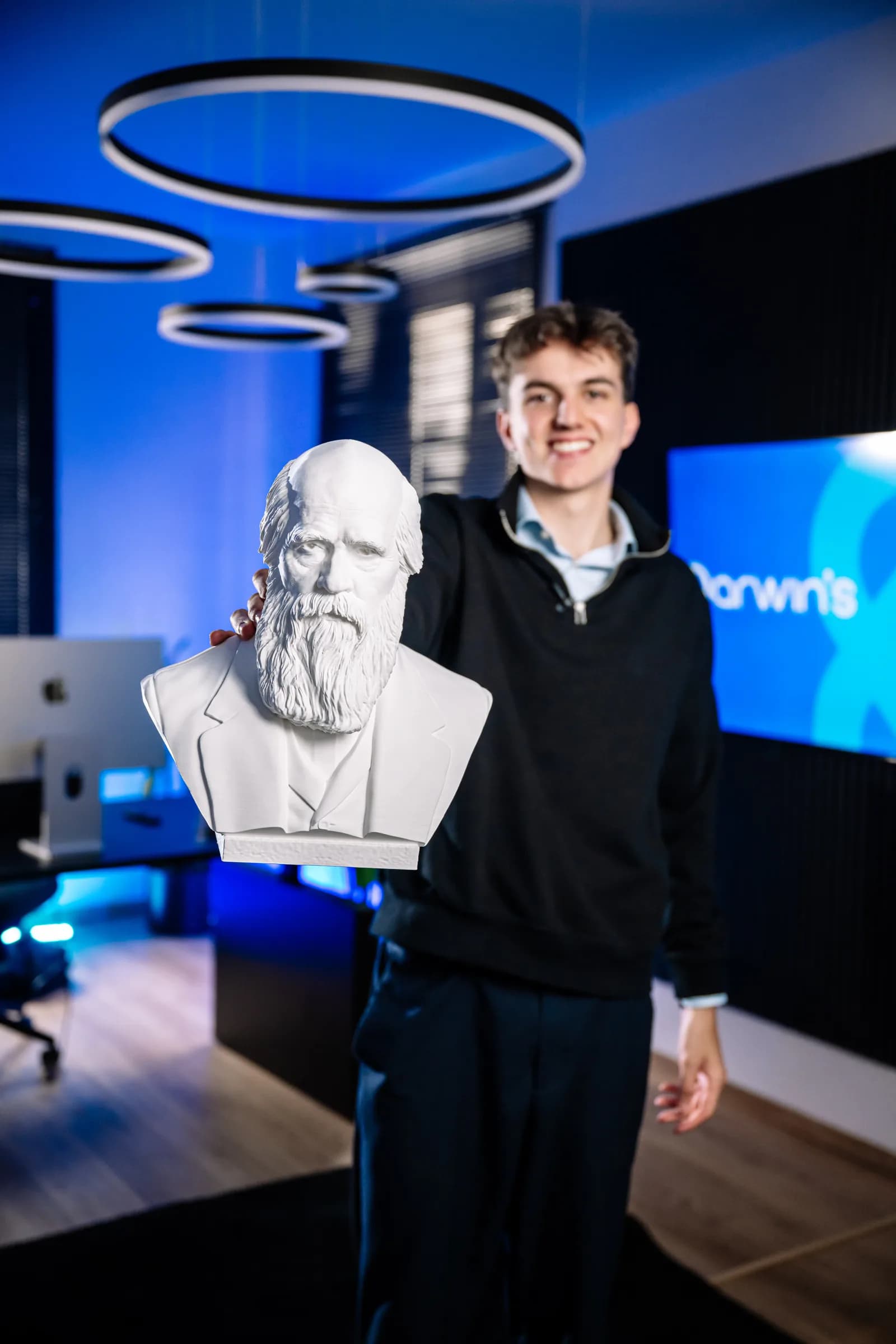 Leon Dapoz, Gründer von darwin's, hält im Büro in Brixen eine Büste von Charles Darwin in die Kamera