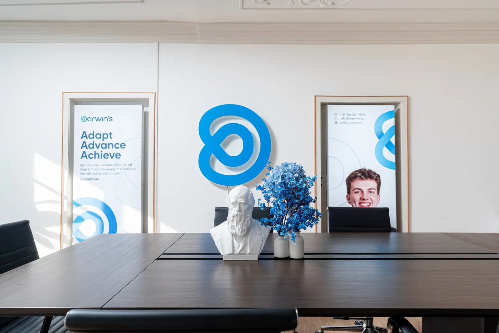 Büste von Charles Darwin auf dem Konferenztisch vor dem darwin's Logo im Büro in Brixen
